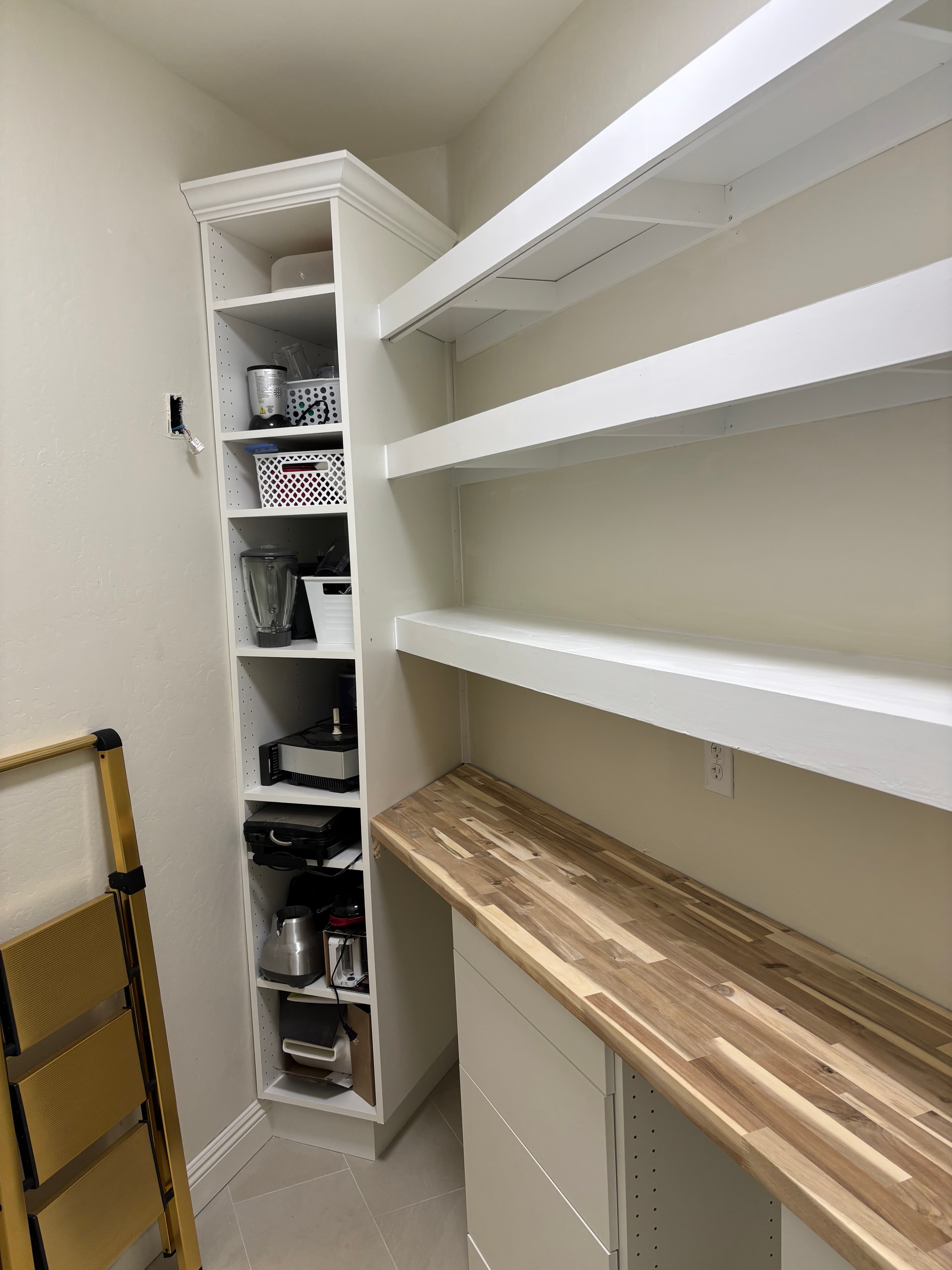 White pantry featuring a butcher block countertop, floating shelves, and a tall appliance cabinet.